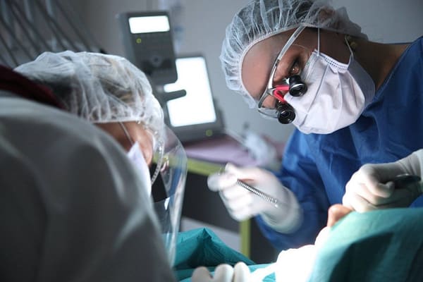 oral and maxillofacial surgeon operating with magnifying loops